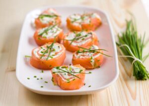 rulouri de somon afumat lchf cu branza philadelphia si iarba ciorii pe platou alb