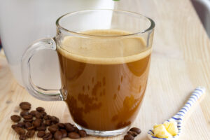 ceasca de cafea bulletproof, cafea low carb high fat cu unt si ulei de cocos, alaturi de boabe de cafea
