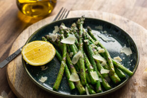 grilled green asparagus with parmesan and lemon zest on a green plate in a rustic kitchen