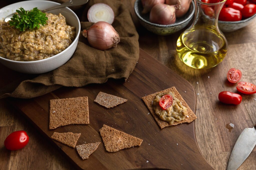 Romanian aubergine caviar in a bowl served on a rustic table with onions and tomatoes