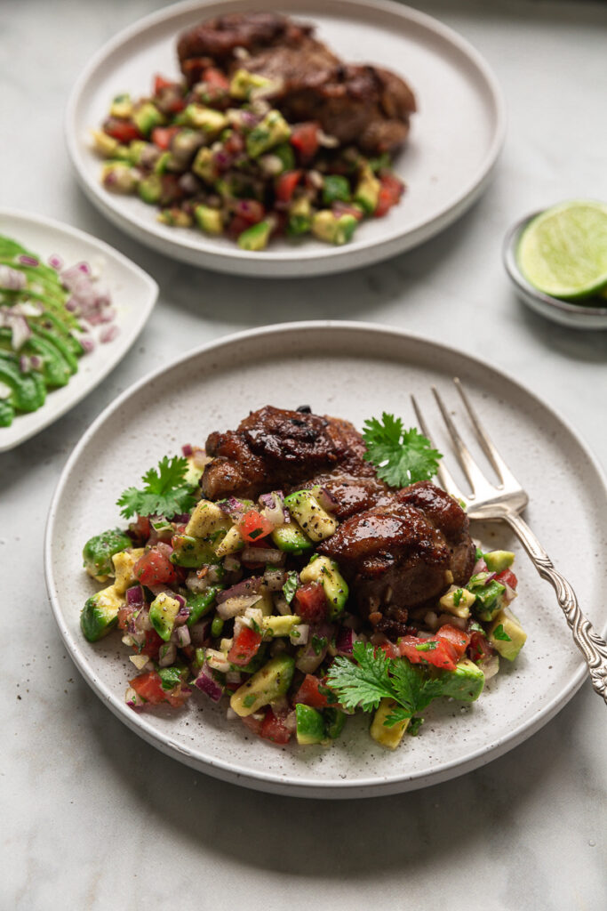 pulpe de pui dezosate la gratar cu salsa de avocado si rosii pe farfurii albe pe masa