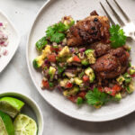 pulpe de pui dezosate la gratar cu salsa de avocado si rosii pe farfurii albe pe masa