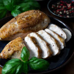 piept de pui la cuptor feliat pe farfurie cu frunze proaspete de busuioc