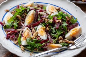 Salata keto cu oua fierte – reteta cu rucola, radicchio, sfecla si nuci pe un platou oval