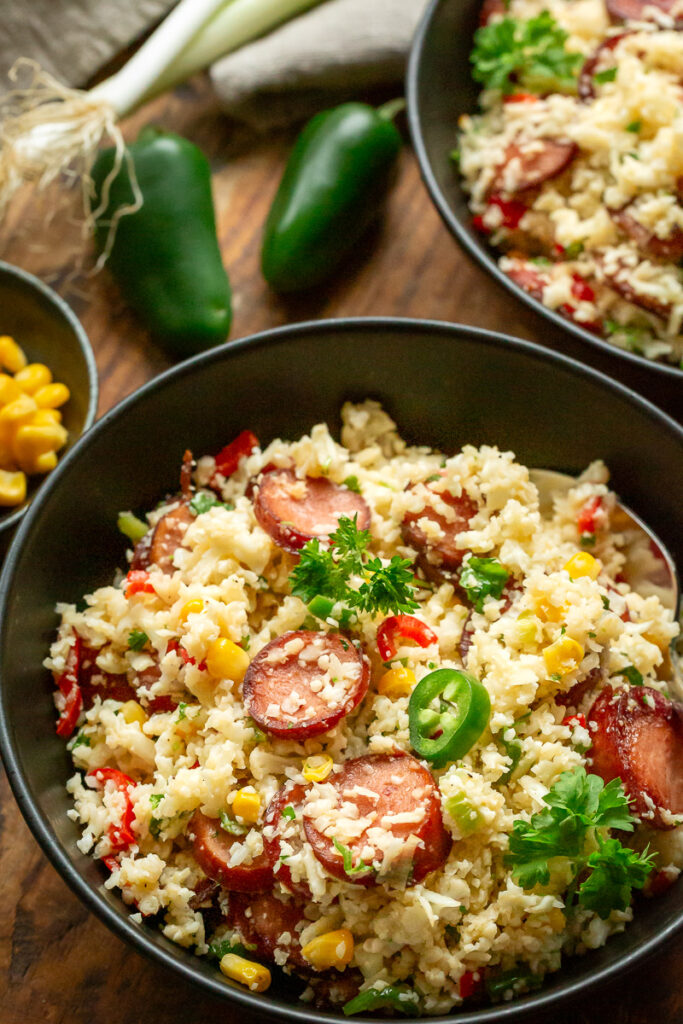 orez mexican din conopida, cu chorizo si legume, jalapeno, porumb, intr-un castron negru