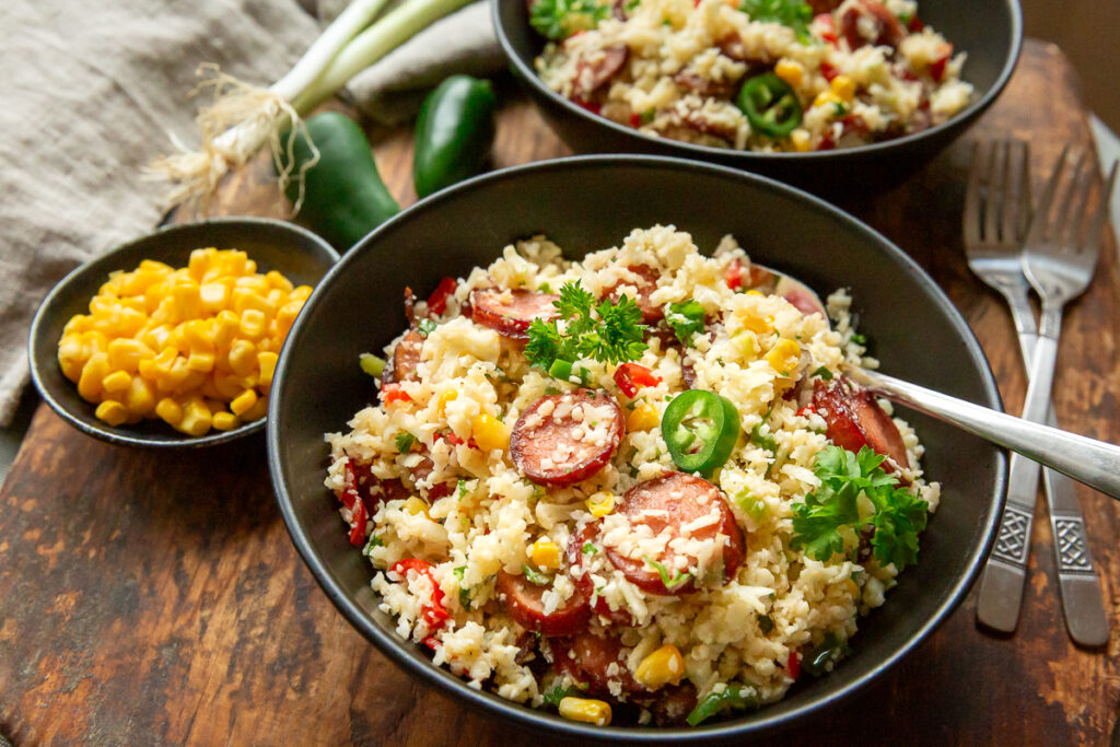 orez mexican din conopida, cu chorizo si legume, jalapeno, porumb, intr-un castron negru