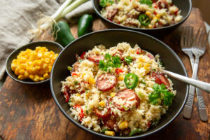 orez mexican din conopida, cu chorizo si legume, jalapeno, porumb, intr-un castron negru