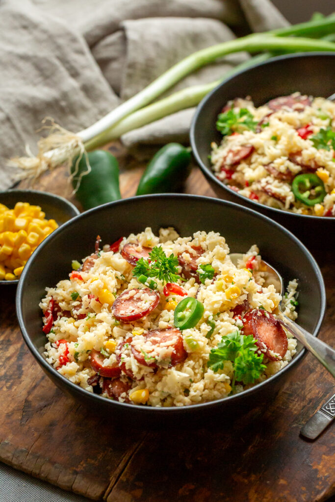 orez mexican din conopida, cu chorizo si legume, jalapeno, porumb, intr-un castron negru