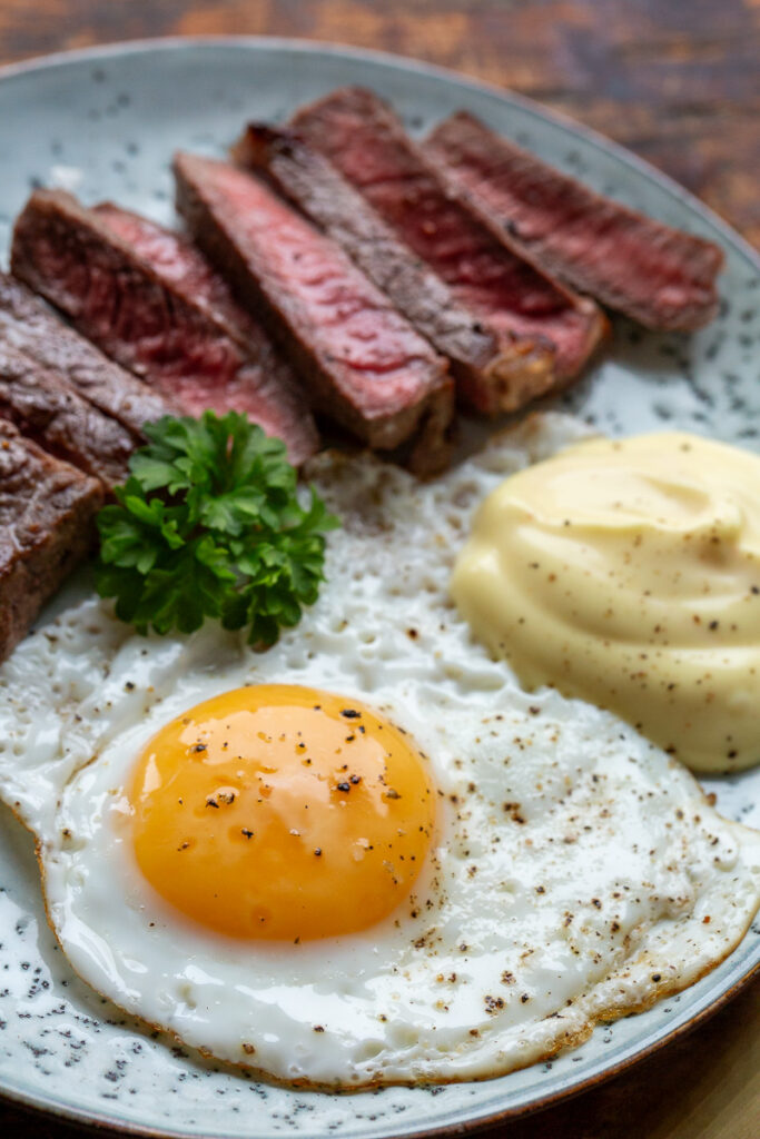 Steak and Eggs keto – friptura felii cu oua si sos olandez pe o farfurie