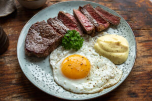 Steak and Eggs keto – friptura felii cu oua si sos olandez pe o farfurie